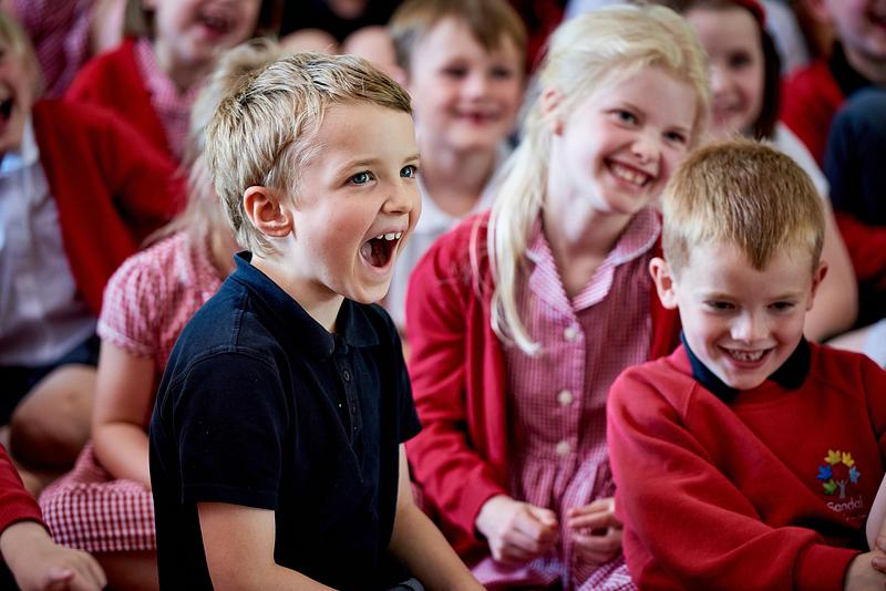 Children smiling and laughing at a performance